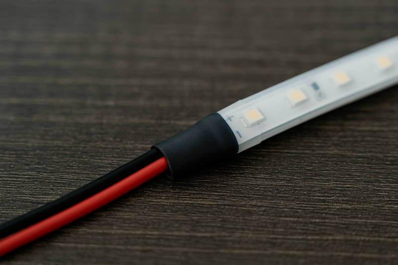 A close-up of a perfectly soldered and heat-shrunk connection on an outdoor LED strip