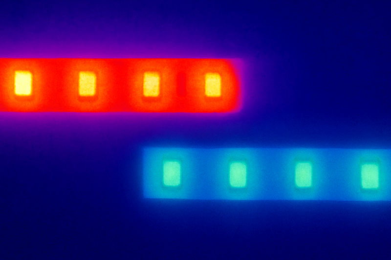 A close-up thermal camera shot of two LED strips side by side. One strip glows angry red (hot) while the other is cool blue, despite both emitting the same amount of visible light.