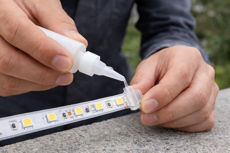 An installer using a correct end cap and glue to seal the cutting point of an LED strip outside